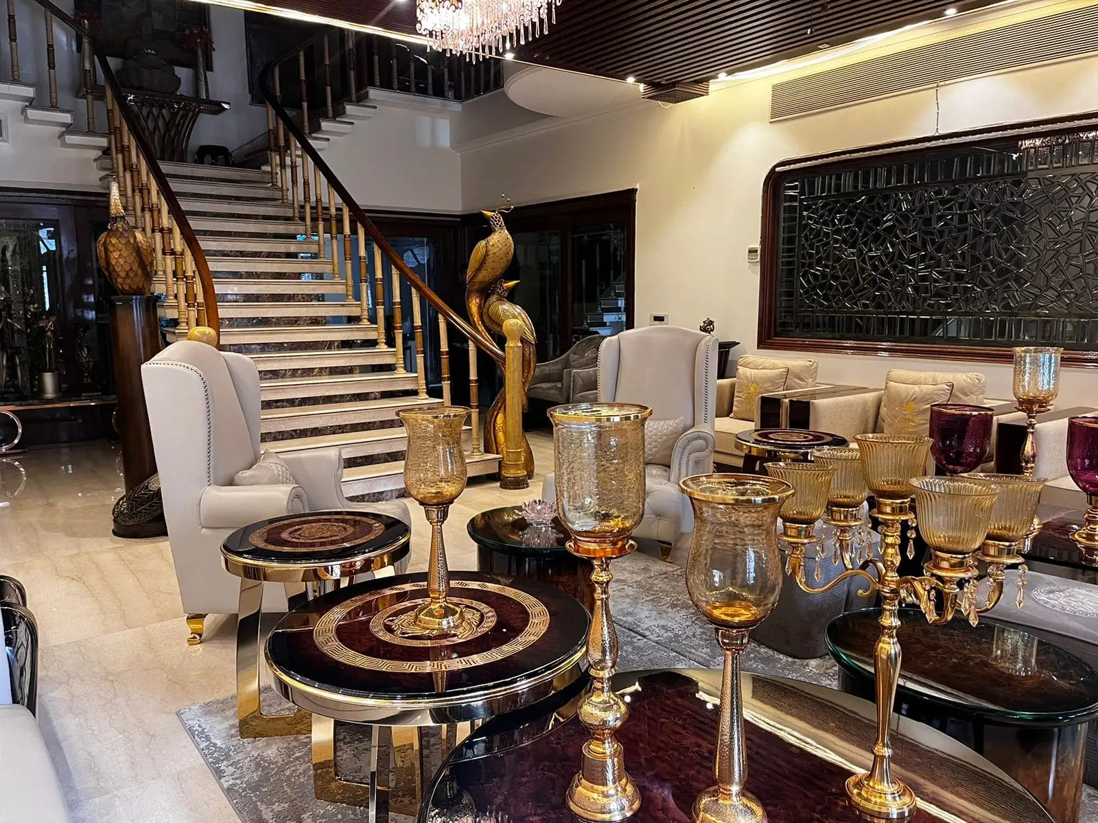 Luxury living room with marble staircase, gold peacock statues and decorative glass vases